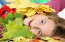 Close-up of a pretty girl lying in a pile of multicolored autumn leaves