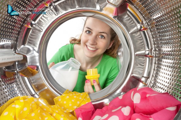 Jeune femme charge du linge de couleur dans une machine à laver. vue de l'intérieur du tambour