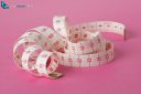Measuring tape isolated on pink background and partially unwound into a spiral