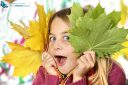 Pretty little girl holding autumn leaves on white background