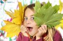 Pretty little girl holding autumn leaves on white background