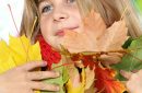 girl playing with a bunch of autumn leaves