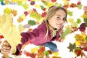 Little girl playing with autumn leaves on white background