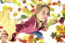Little girl playing with autumn leaves on white background