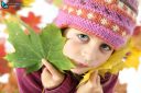 Autumnal mood of a little girl in yellow autumn leaves looking at camera