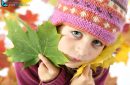 Autumnal mood of a little girl in yellow autumn leaves looking at camera