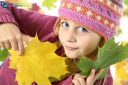 Portrait of young girl in autumn with multicolored leaves, looking at the camera