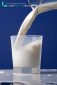 Milk from jug poured into a glass. Milk overflows on the table