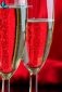 Close up of two glasses of champagne on red background