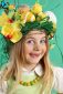 Happy Easter day. cute girl with festive Easter hairstyle made of yellow easter eggs, spring flowers and bird feathers.