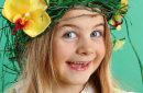 Happy Easter day. cute girl with festive Easter hairstyle made of yellow easter eggs, spring flowers and bird feathers.