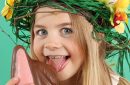 Young girl with Easter eggs on her head eats a chocolate bunny