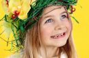 Smiling Happy Young Girl Wearing Headdress of Spring Flowers, Easter Eggs and Feathers.