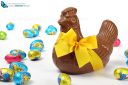 Chocolate hen with yellow ribbon and colorful Easter eggs, isolated on white background