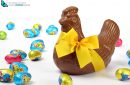 Chocolate hen with yellow ribbon and colorful Easter eggs, isolated on white background