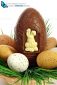 basket of Easter eggs on green grass with a large chocolate egg and a white rabbit