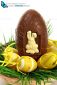 Basket of yellow Easter eggs laid on fresh grass with a large chocolate egg on white background