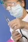 old nurse with protective mask and gloves prepares injection of vaccine or medicine for disease prevention with glass syringe and large needle