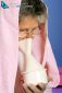 Elderly woman with towel over head inhales essential oil vapor to treat colds and sore throat