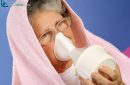 65 year old woman with towel over head inhaling essential oil vapor as alternative therapy