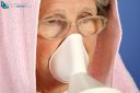 healthcare concept, colds, rhinitis and sore throat. Old gray-haired woman uses inhaler to infuse medicine and heal herself.