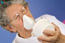 Close-up 65-year-old sick woman using inhaler to treat colds and sore throat