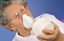 Close-up 65-year-old sick woman using inhaler to treat colds and sore throat