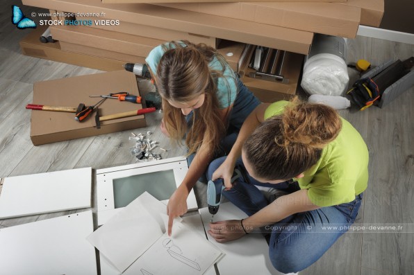 Deux jeunes filles assemblent un meuble de chambre en kit