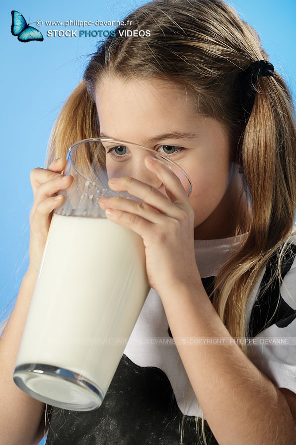Enfant avec des couettes et un t-shirt couleur vache boit un enorme verre de lait