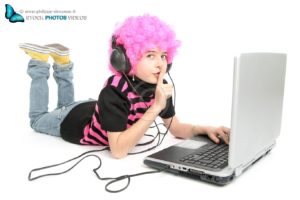 Jeune fille au cheuveux rose ecrivant sur un ordinateur portable